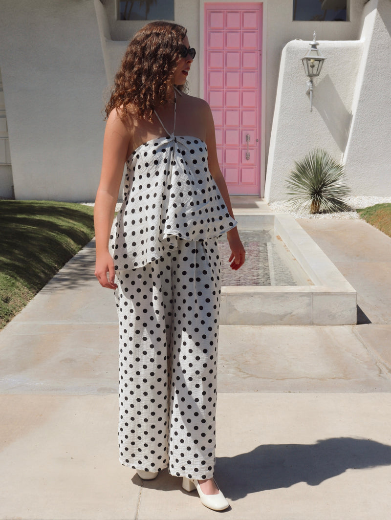 Woman in a polka dot set standing in front of a pink door.