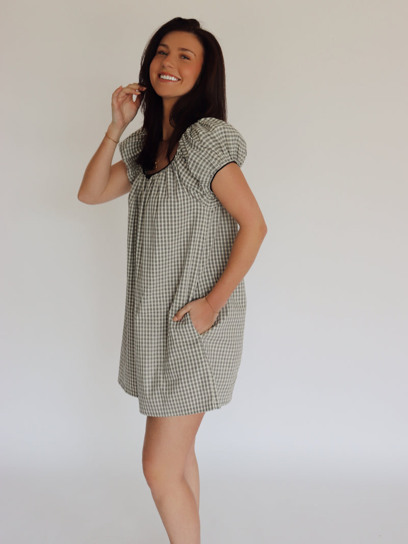 Woman wearing a checkered dress against a plain background