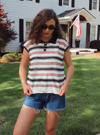 Woman wearing a striped shirt and denim shorts standing in front of a house