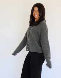 Woman wearing a gray sweater cardigan with button details against a white background