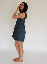 Woman wearing a denim dress against a plain background