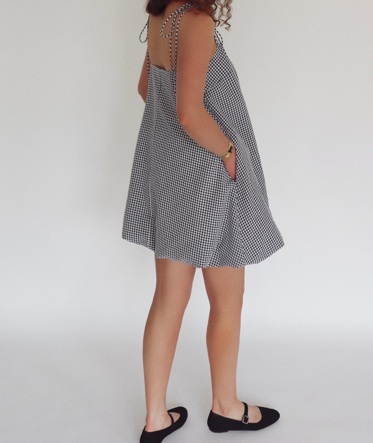 Person wearing a black and white checkered dress on a plain background