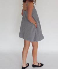Person wearing a black and white checkered dress on a plain background