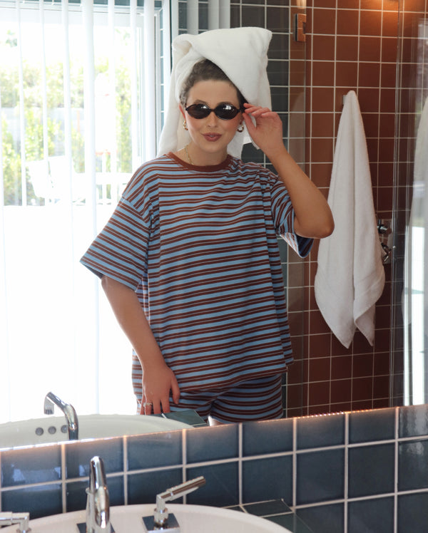 Person wearing a striped outfit with a towel on their head in a bathroom.