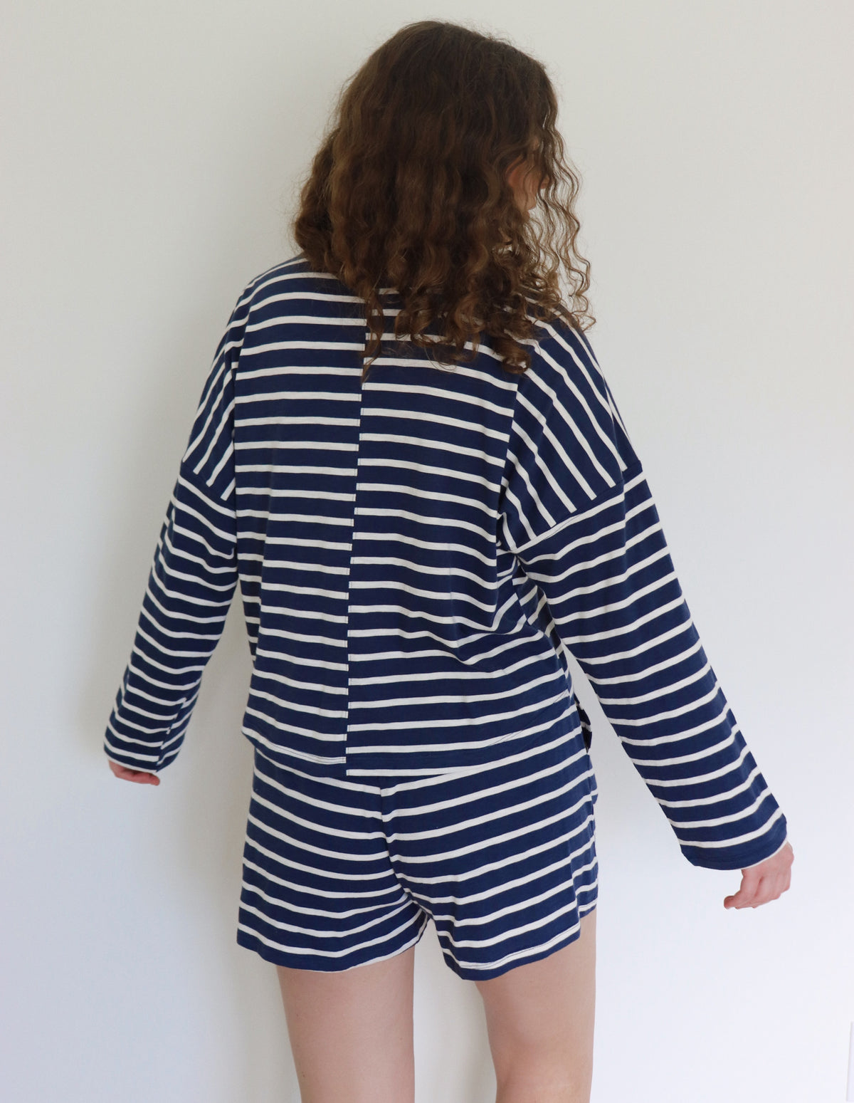 Woman wearing a navy and white striped outfit against a plain background