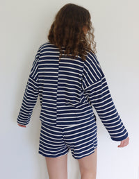Woman wearing a navy and white striped outfit against a plain background