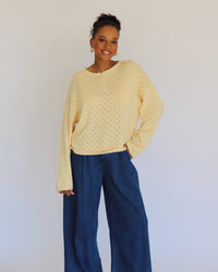 Person wearing a yellow textured sweater and blue pants against a white background