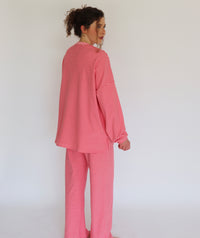 A woman wearing a pink striped lounge set, shown from the back and side against a plain white background.