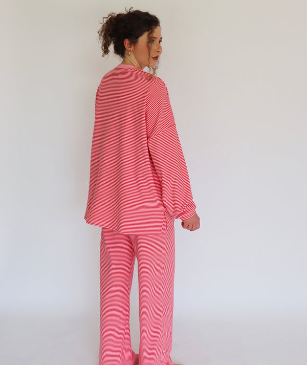 A woman wearing a pink striped lounge set, shown from the back and side against a plain white background.
