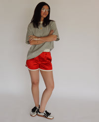 Person wearing a striped shirt and red shorts with black shoes on a plain background