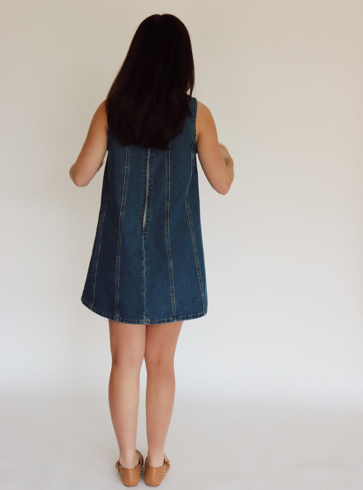Woman wearing a denim dress against a plain background