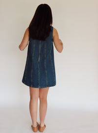 Woman wearing a denim dress against a plain background