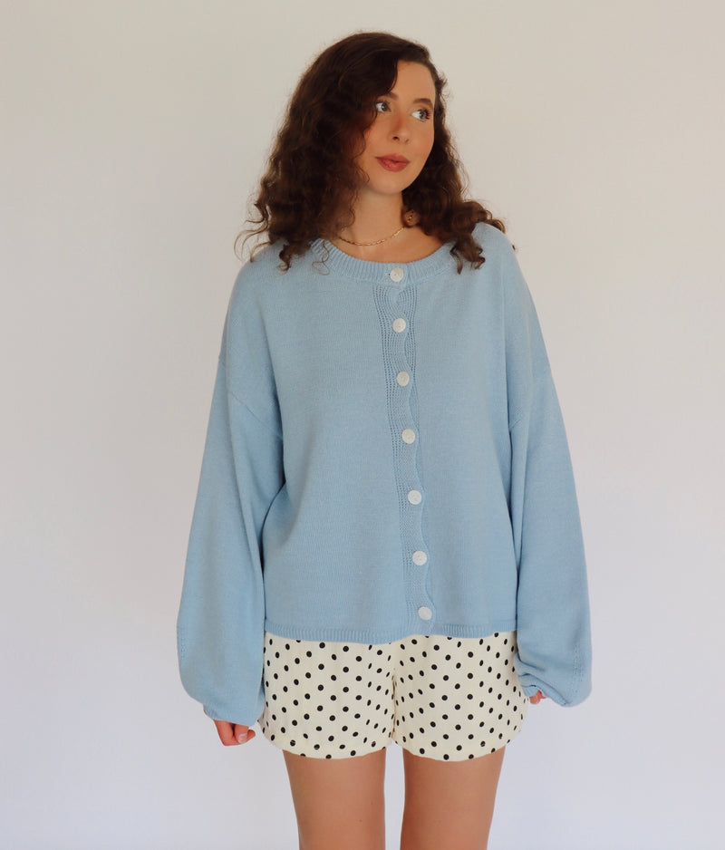 woman wearing a blue cardigan and polka dot shorts