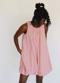 Woman wearing a pink dress with white polka dots on it against a white background