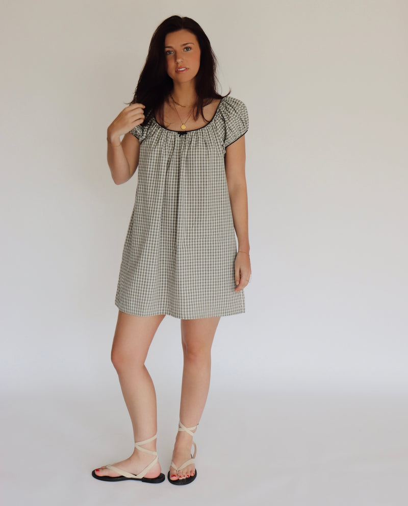 Woman wearing a checkered dress against a plain background