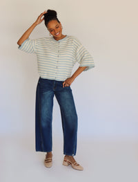 Woman wearing a striped cardigan and jeans against a plain background