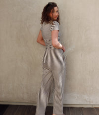 Woman wearing a dark gray and white striped outfit against a plain wall.