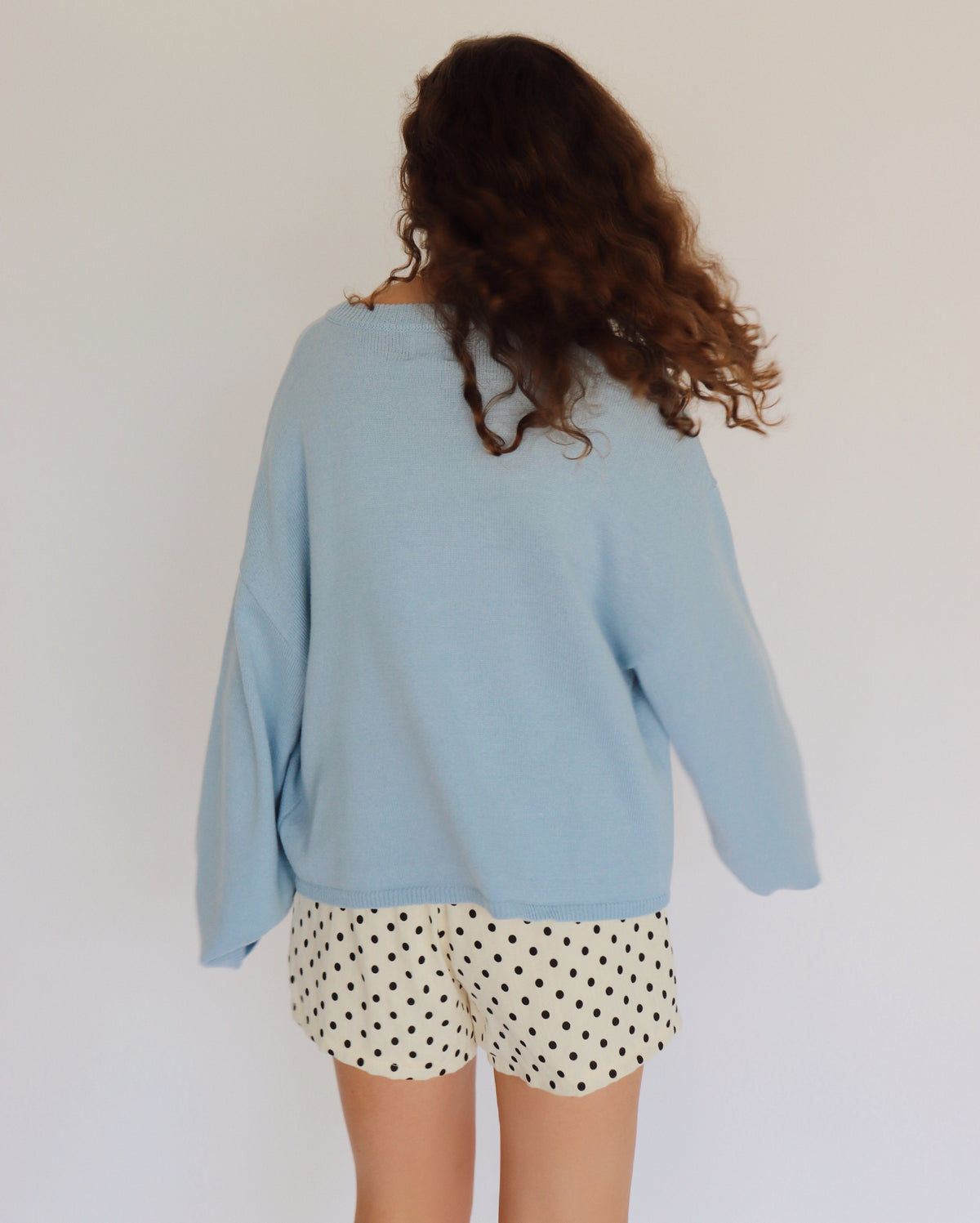 woman wearing a blue cardigan and polka dot shorts
