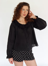 Woman wearing a black blouse and polka dot shorts on a white background