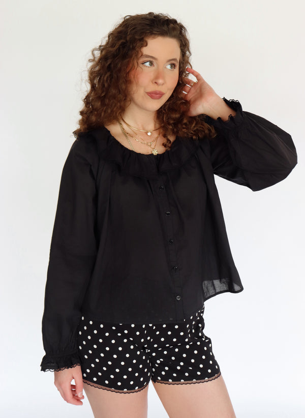 Woman wearing a black blouse and polka dot shorts on a white background