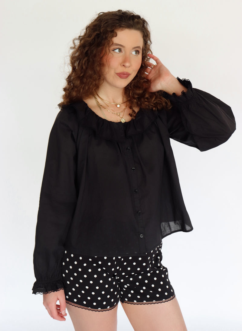 Woman wearing a black blouse and polka dot shorts on a white background