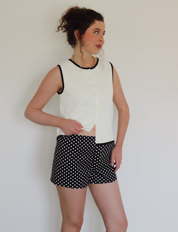 Woman in a white top with black polka dot shorts