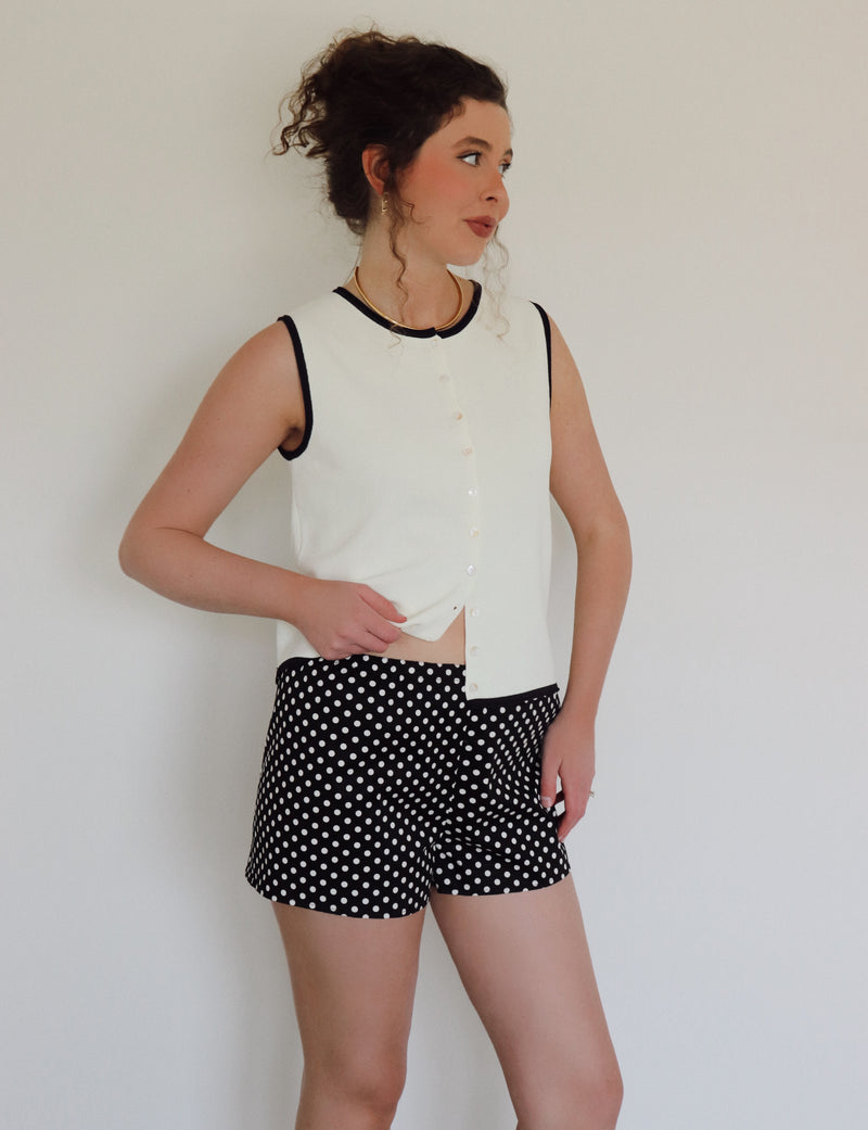 Woman in a white top with black polka dot shorts