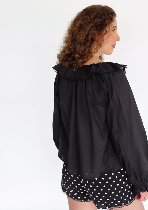 Woman wearing a black blouse and polka dot shorts on a white background