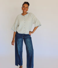 Woman wearing a striped cardigan and jeans against a plain background