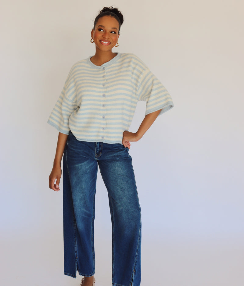 Woman wearing a striped cardigan and jeans against a plain background