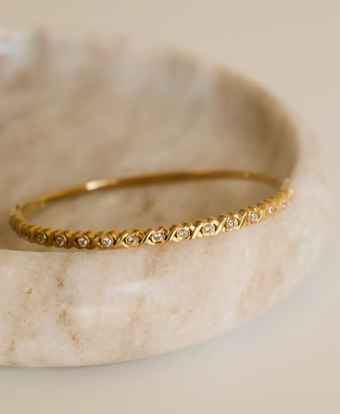Gold bracelet with small diamonds on a marble surface