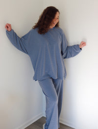 Woman wearing a blue set against a white wall
