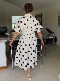 Woman in a polka dot dress walking in a modern kitchen.