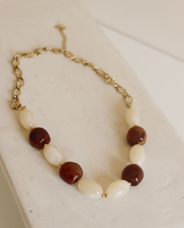 Necklace with brown and white beads on a light surface