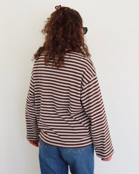 Person wearing a striped shirt and blue jeans against a white background