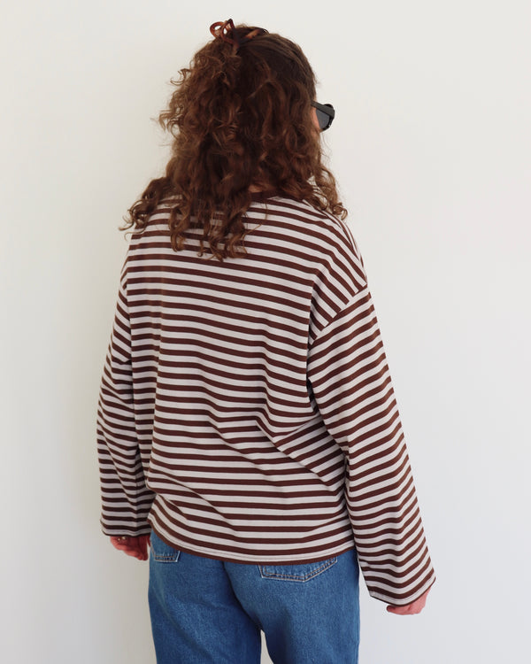 Person wearing a striped shirt and blue jeans against a white background
