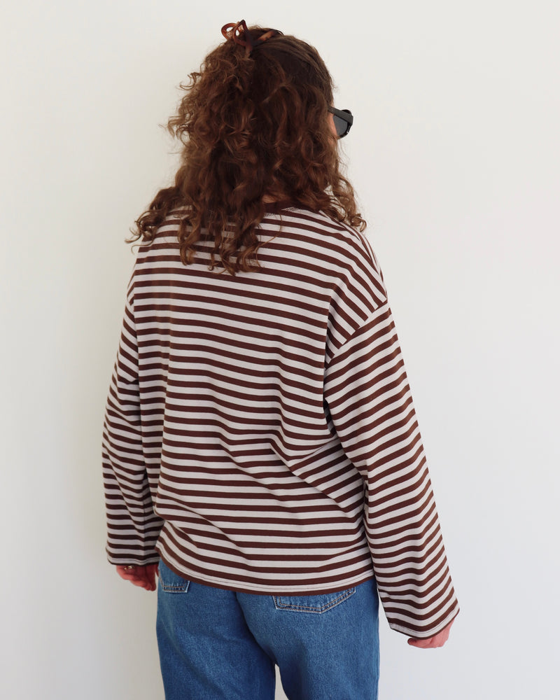 Person wearing a striped shirt and blue jeans against a white background