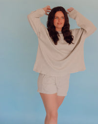 Woman wearing a gray lounge set against a light blue background