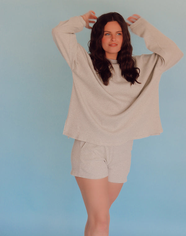 Woman wearing a gray lounge set against a light blue background