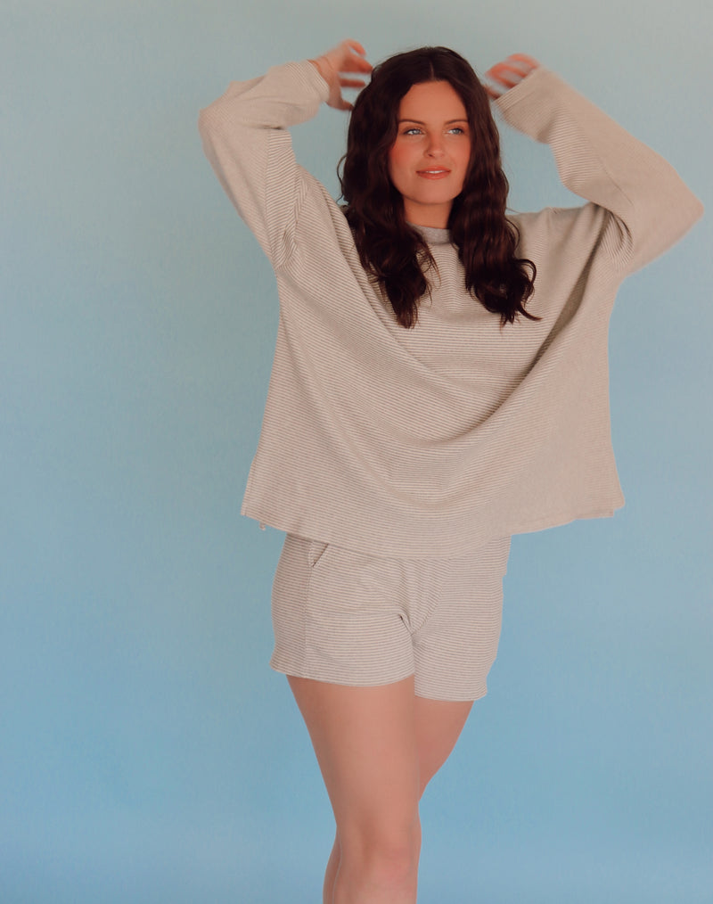 Woman wearing a gray lounge set against a light blue background