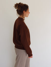 Person wearing a brown sweater and striped pants against a white background