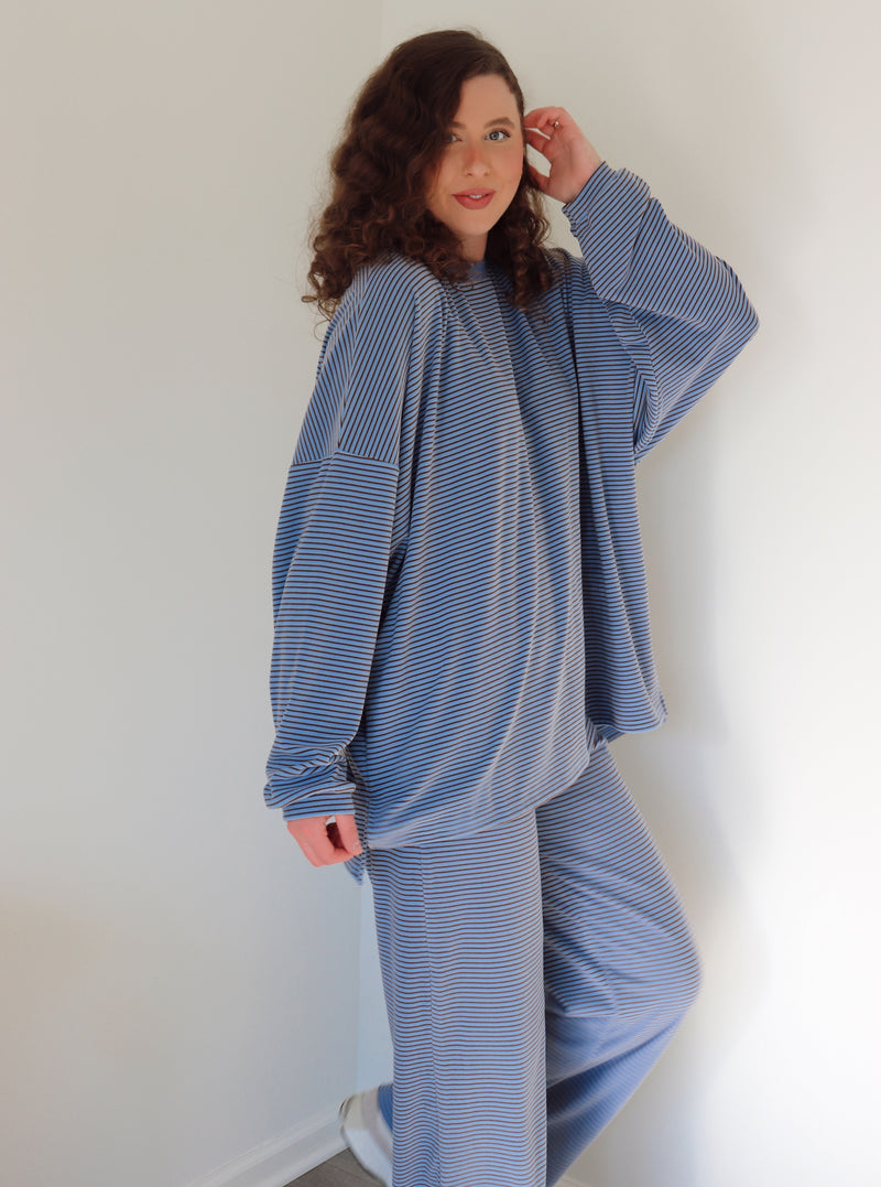 Person wearing a blue striped outfit against a white wall