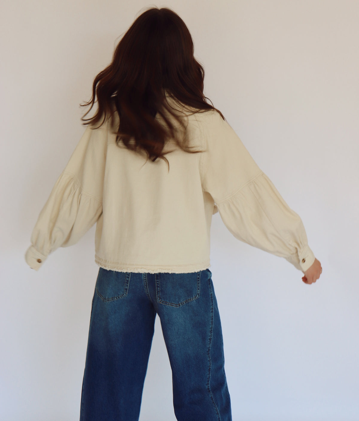 Woman wearing a beige jacket with buttons against a plain background