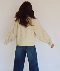 Woman wearing a beige jacket with buttons against a plain background