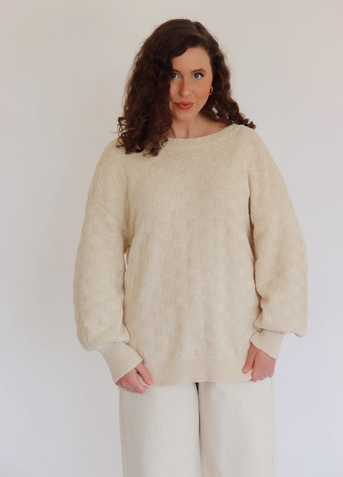 Woman wearing a beige sweater against a plain background