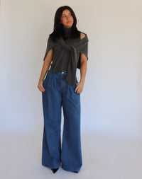 Woman wearing a dark gray turtleneck and blue jeans against a white background