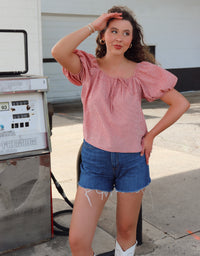 Woman wearing a red gingham top with blue jean shorts