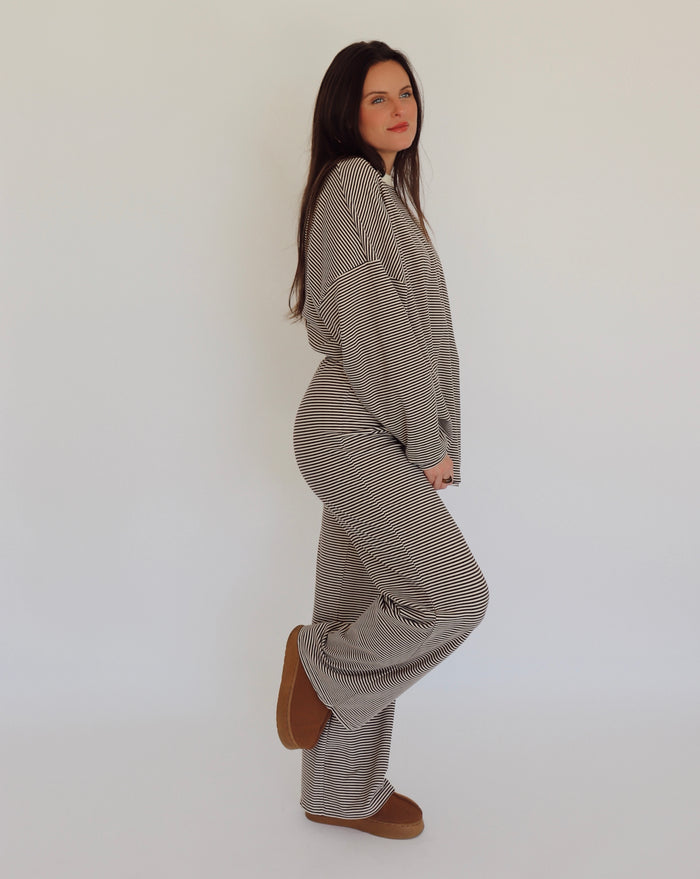 Woman wearing a matching brown and cream striped outfit on a white background