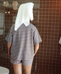 Person wearing a striped outfit with a towel on their head in a bathroom.