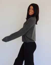 Woman wearing a gray sweater cardigan with button details against a white background